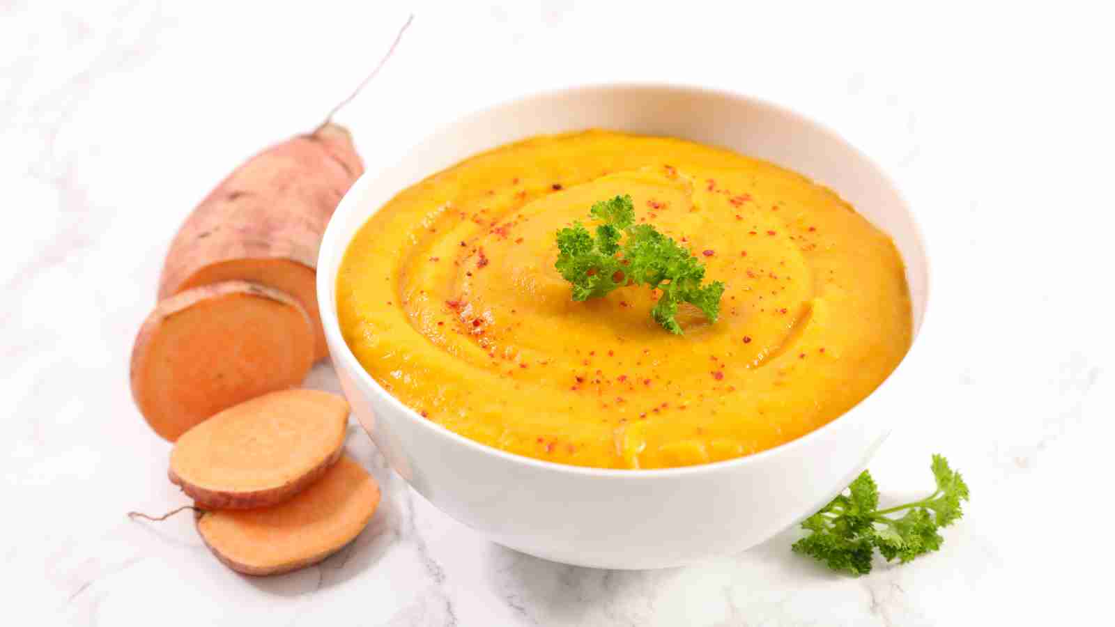 A bowl of sweet potato soup with slices of sweet potatoes on the side.