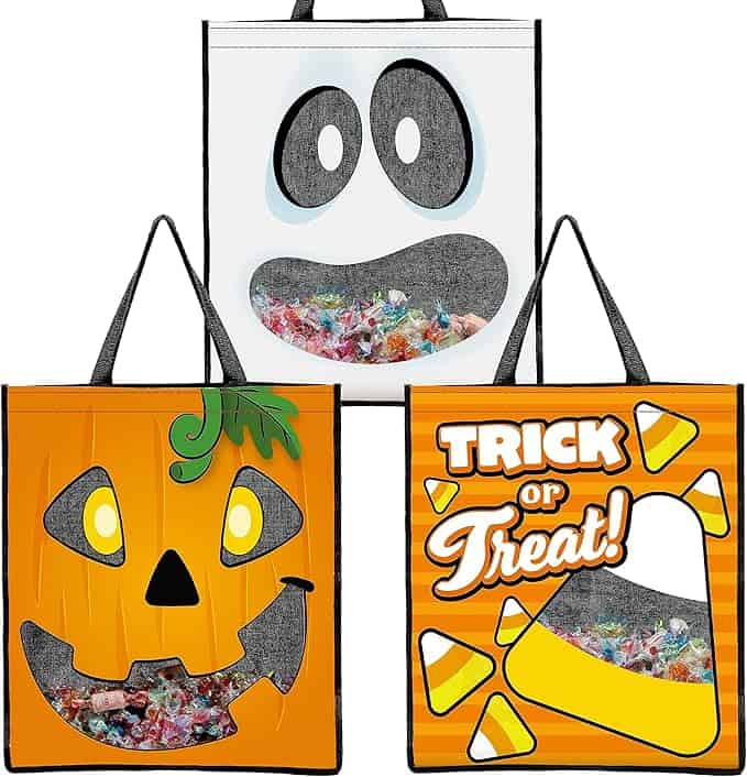 Three Halloween-themed tote bags filled with candy.
