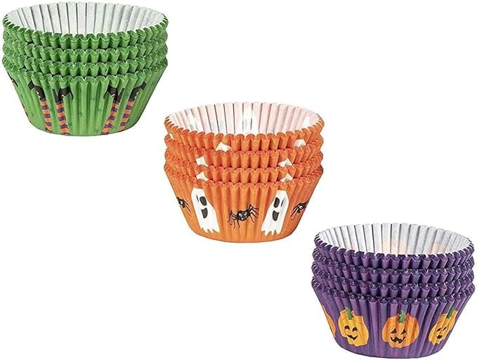 Three stacks of Halloween-themed cupcake liners: green with black bats, orange with ghosts and spiders, purple with jack-o'-lanterns.