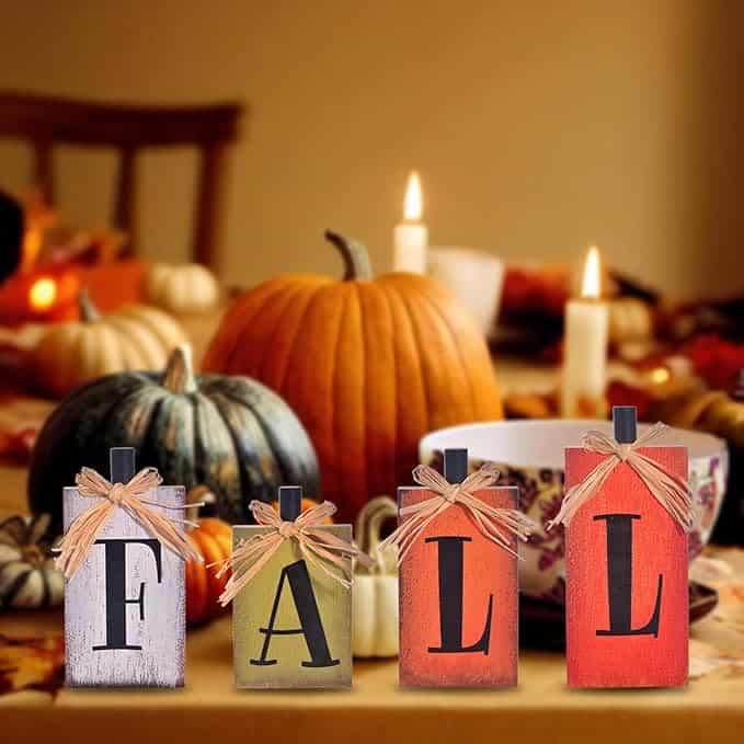 Table decorated for fall with pumpkins, candles, and blocks spelling "FALL" in front.