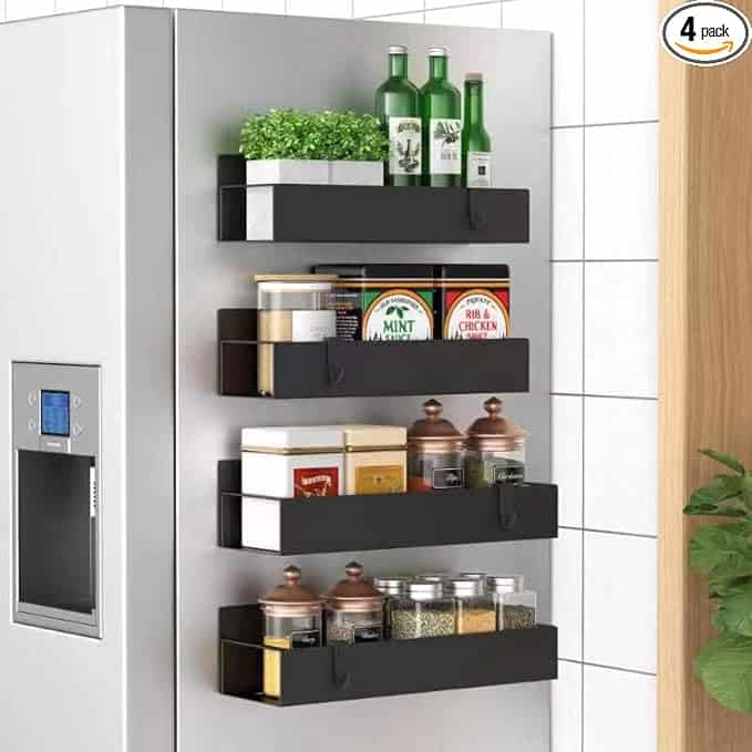 Magnetic shelves on a refrigerator hold bottles, cans, and jars, with plants on top.