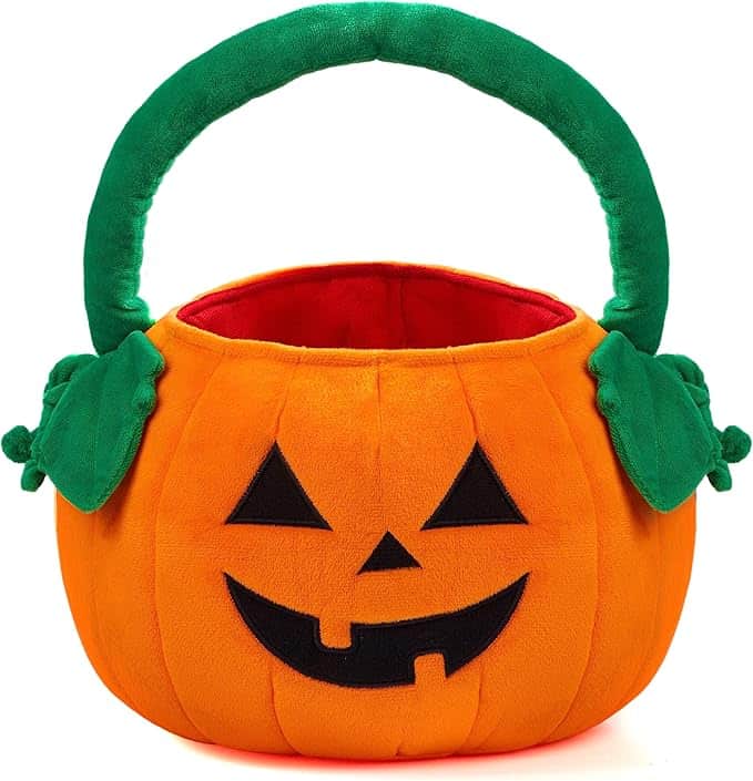 A plush pumpkin-shaped basket with a green handle and green leaf accents, featuring a smiling jack-o'-lantern face.