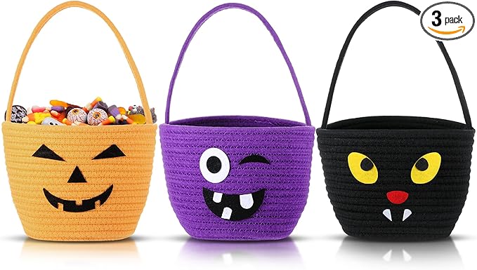 Three Halloween-themed woven baskets: one orange with a pumpkin face filled with candy, one purple with a monster face, and one black with a cat face. Labeled as a 3-pack.