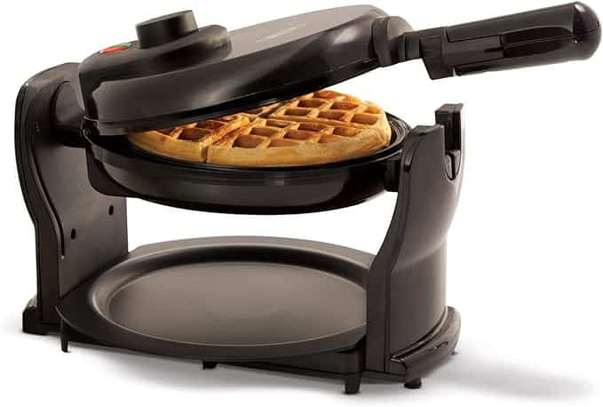 A black flip waffle maker with a waffle inside, partially open, showing the cooking process.