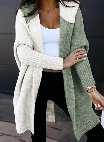 A person in a two-toned cardigan, white and green, with a white top and black pants, standing outdoors.