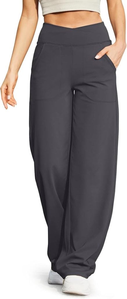 Person wearing high-waisted black wide-leg pants and a beige top, with one hand in their pocket, walking.