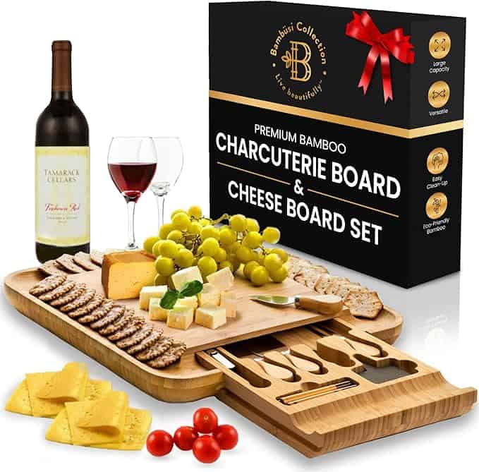 Charcuterie board with cheese, grapes, crackers, tomatoes, and a wine bottle.