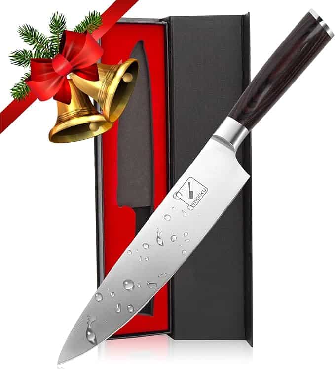 Chef's knife with a polished blade and dark handle, presented in a black and red box, adorned with holiday-themed decor.