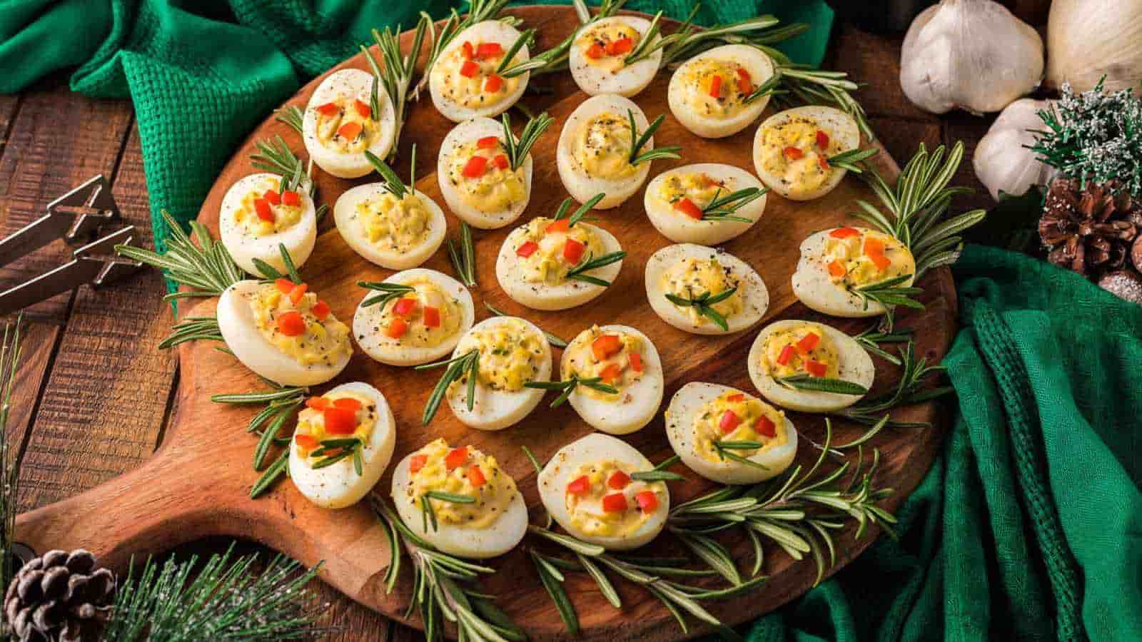 A board with deviled eggs that are decorated for Christmas.