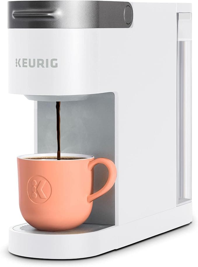 White Keurig coffee machine brewing coffee into a pink mug.