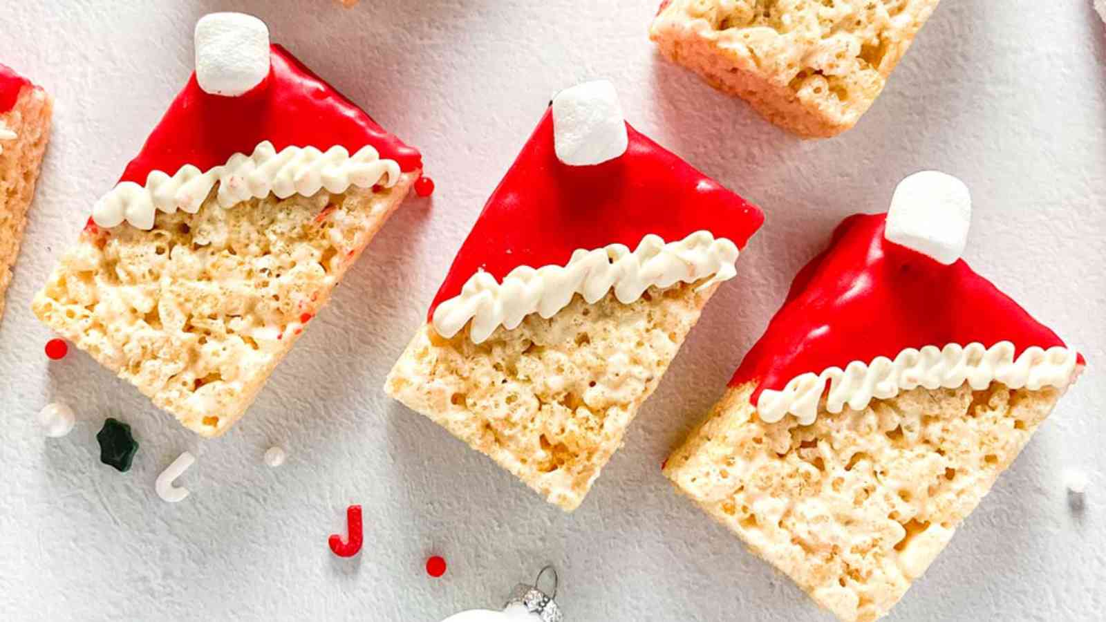 Three rice krispie treats decorated red candy melts and mini marshamllows to look like Santa's hat.