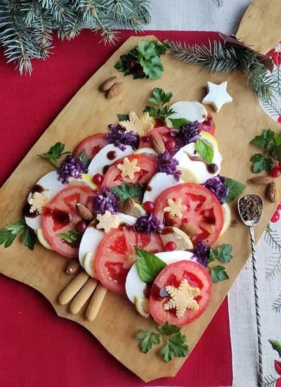 A wooden cutting board with a Caprese Christmas tree salad on it.
