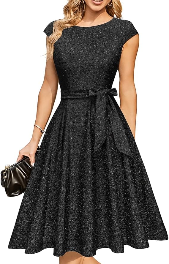 Woman wearing a glittery black dress with cap sleeves and a belt bow, holding a black handbag.