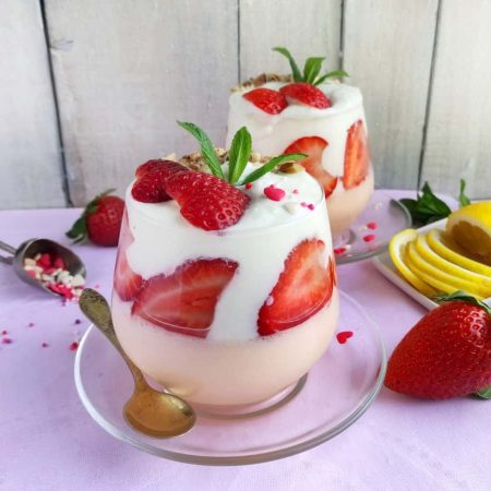 Strawberry yogurt parfait in a stemless wine glass with another one in the background.