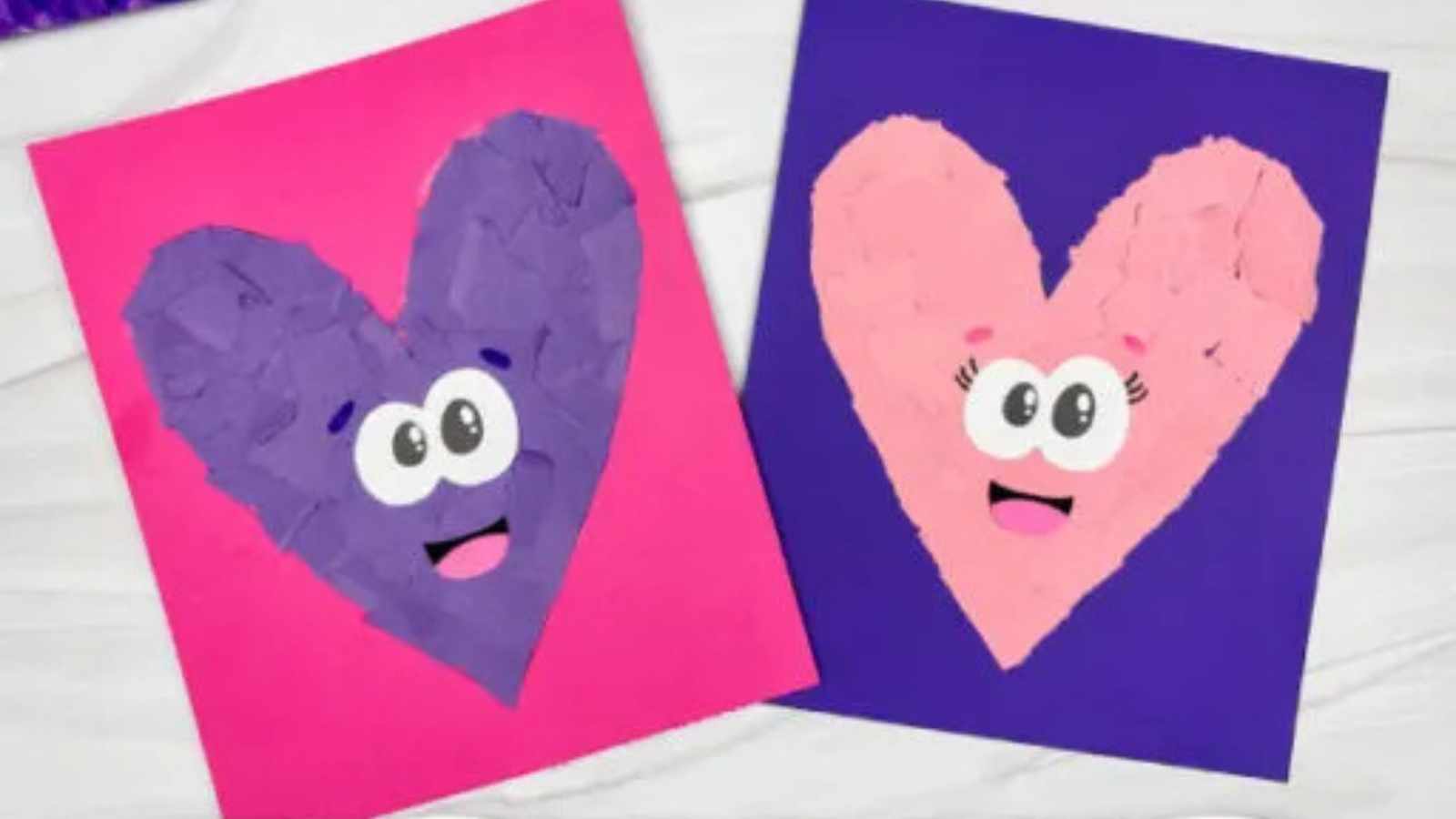 Two heart-shaped art pieces with eyes and mouths, one in purple on a pink background and the other in pink on a purple background, displayed on a white surface.