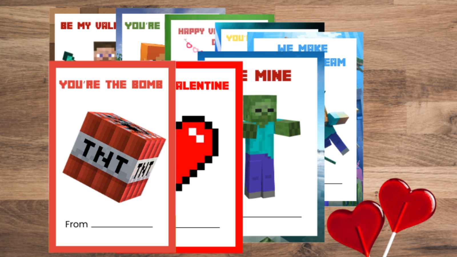 A set of Minecraft-themed Valentine cards featuring graphics like TNT, hearts, and characters, arranged fanned out on a wooden surface with two heart-shaped lollipops.
