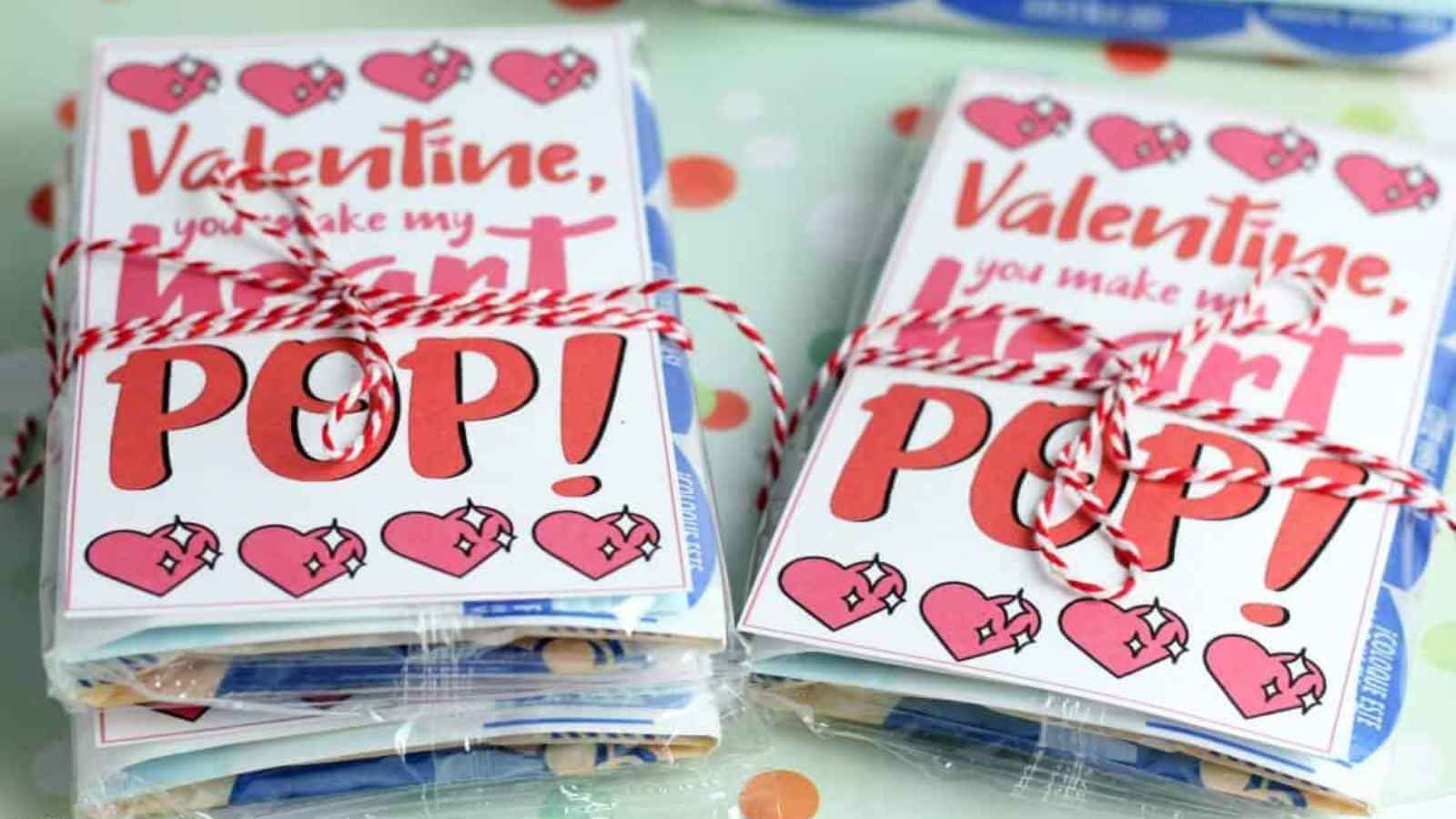 Stacked Valentine's Day cards with "Valentine, you make my heart POP!" text, hearts, and twine, placed atop Pop-Tarts packages.