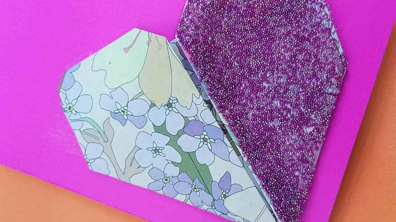 A handmade paper heart with floral print and beaded texture on a bright pink background.