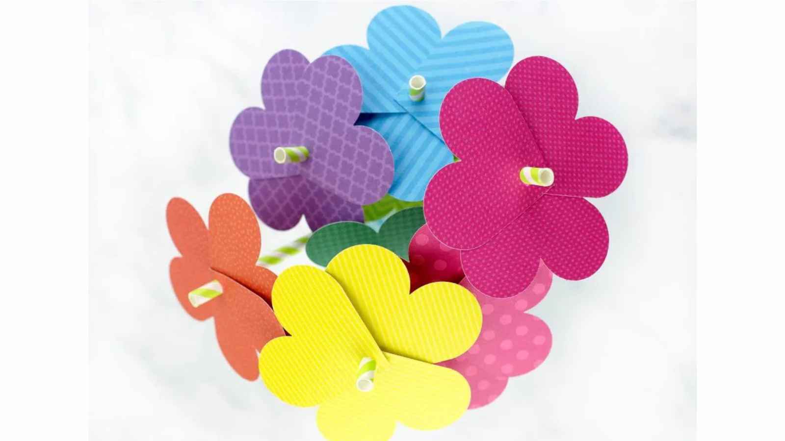 Colorful paper flowers with striped and patterned petals are arranged in a bouquet, viewed from above.