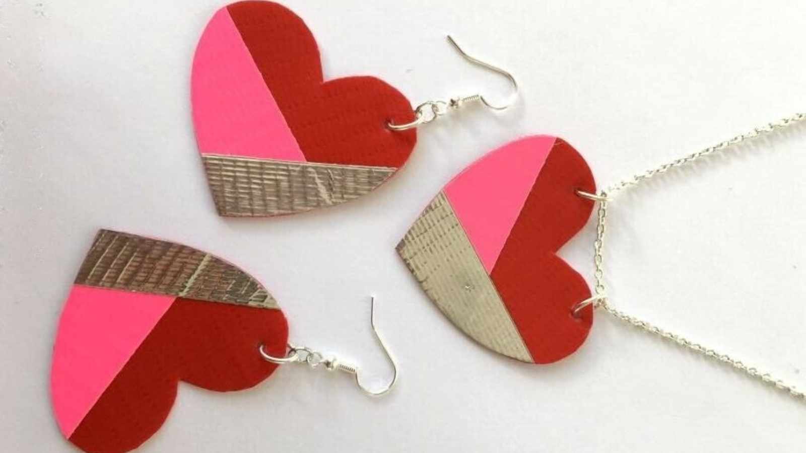 Heart-shaped earrings and a matching necklace in red, pink, and silver tones displayed on a white background.