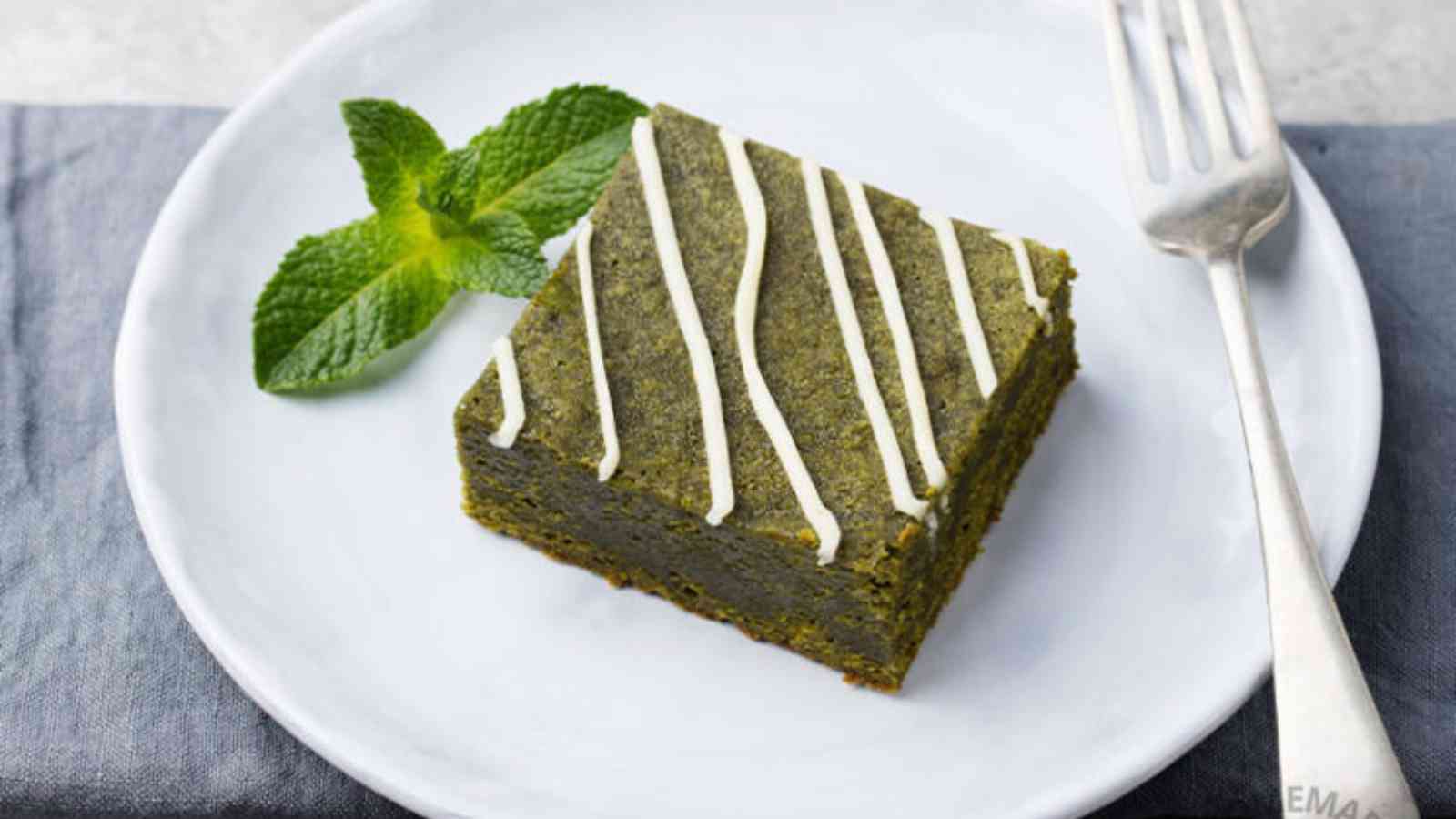 Matcha brownie on a white plate with fork on the side.