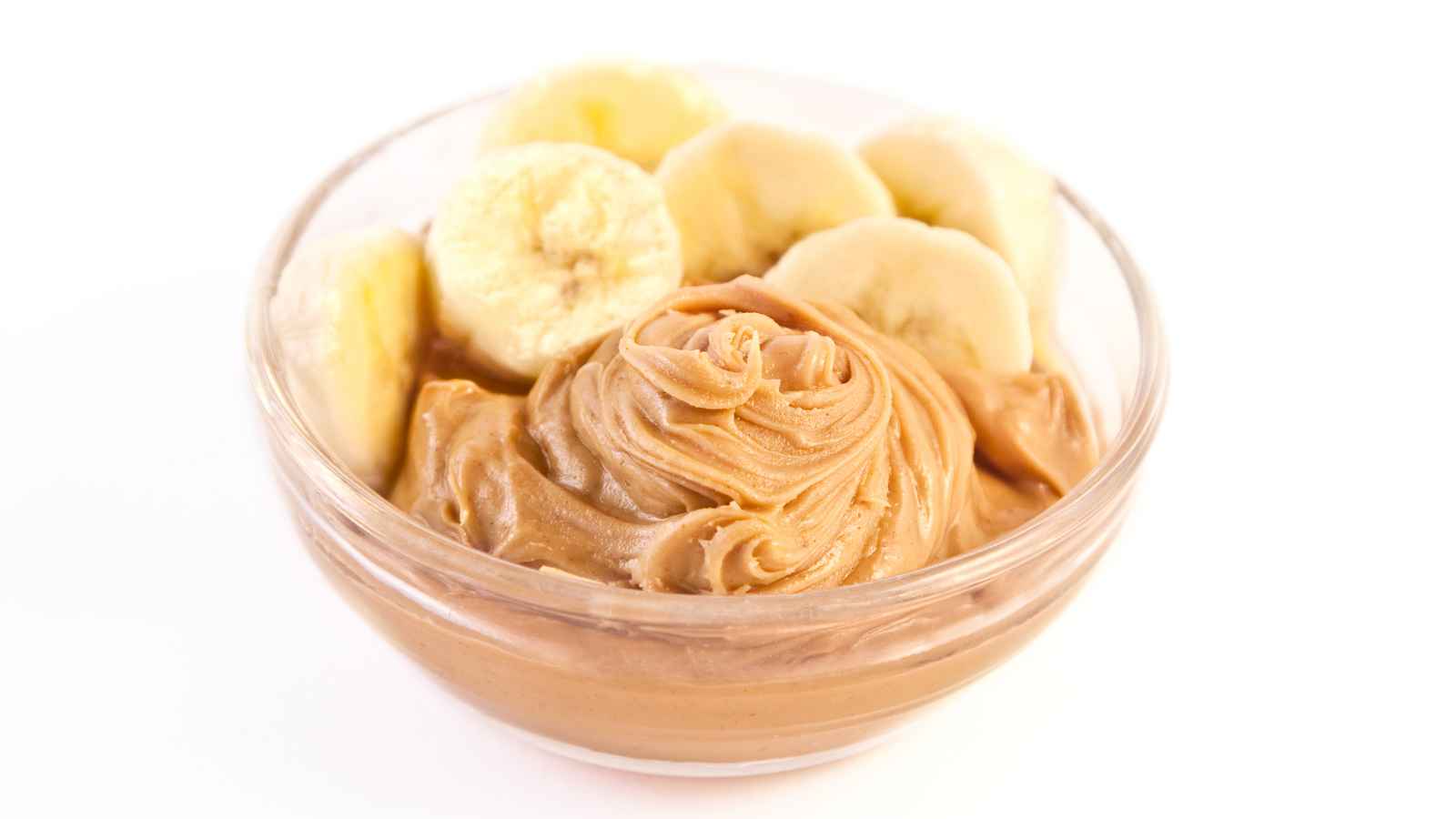 A glass bowl filled with creamy peanut butter, topped with sliced bananas in a circular arrangement.