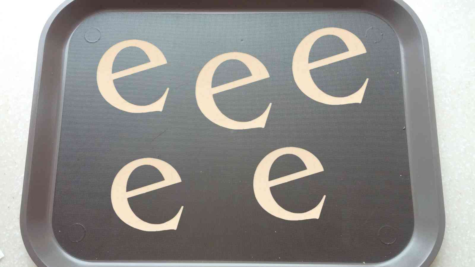 A brown tray with five lowercase letter 'e's evenly spaced across its surface.