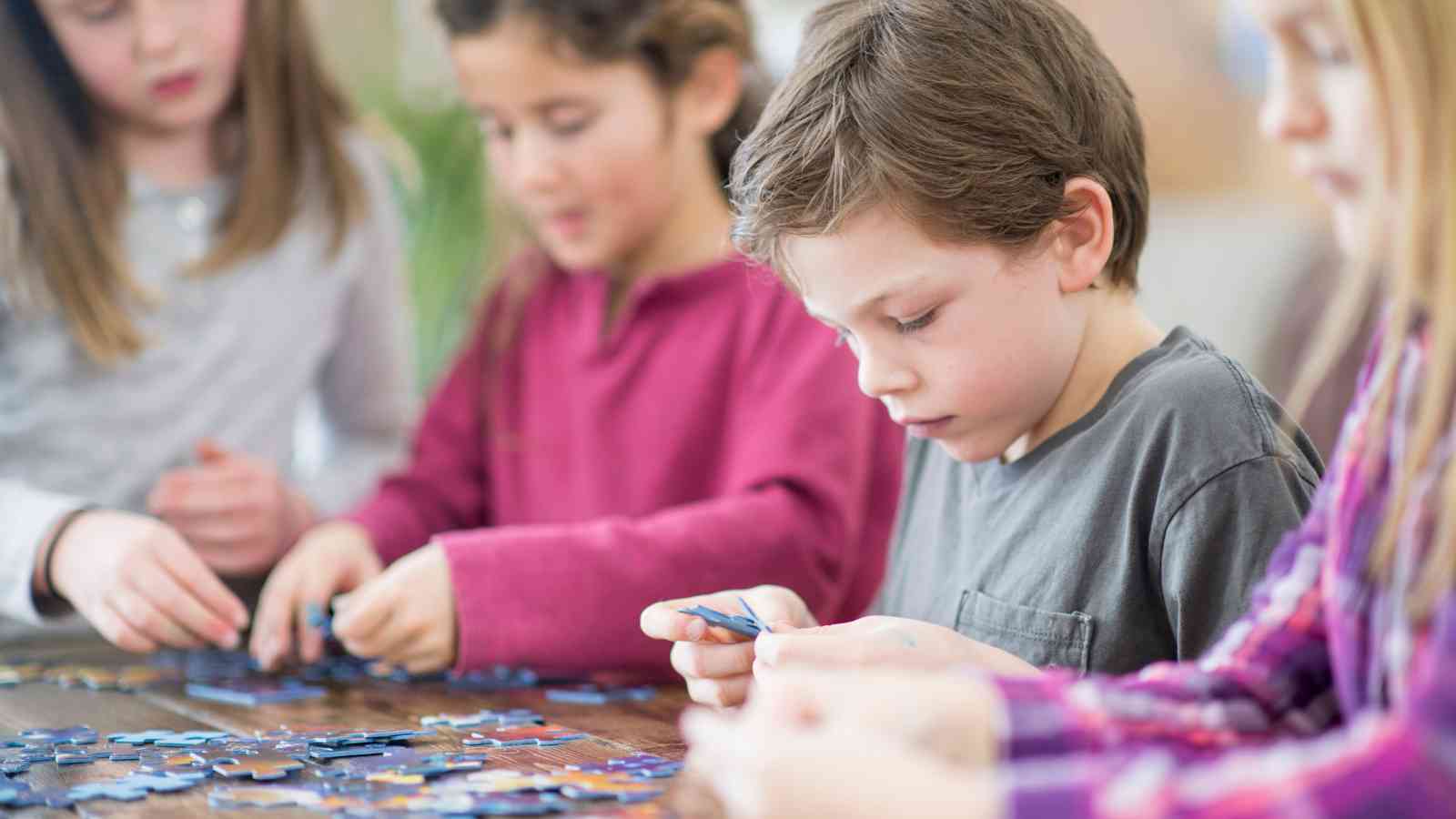 Children focused on assembling a jigsaw puzzle together at a table.