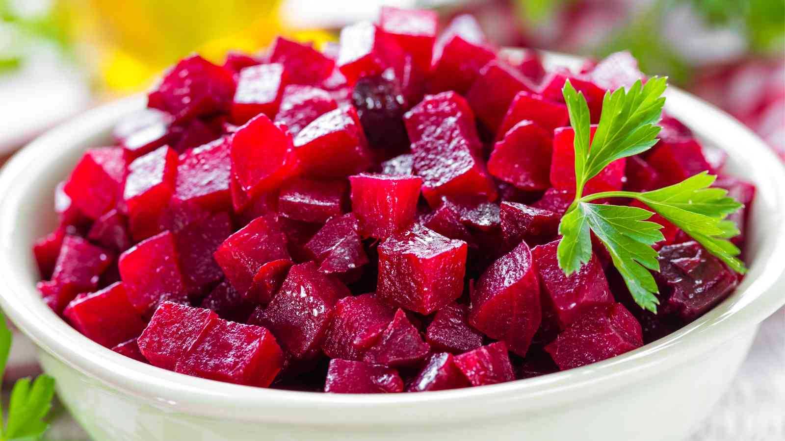A white bowl filled with diced red beets, garnished with a sprig of parsley.