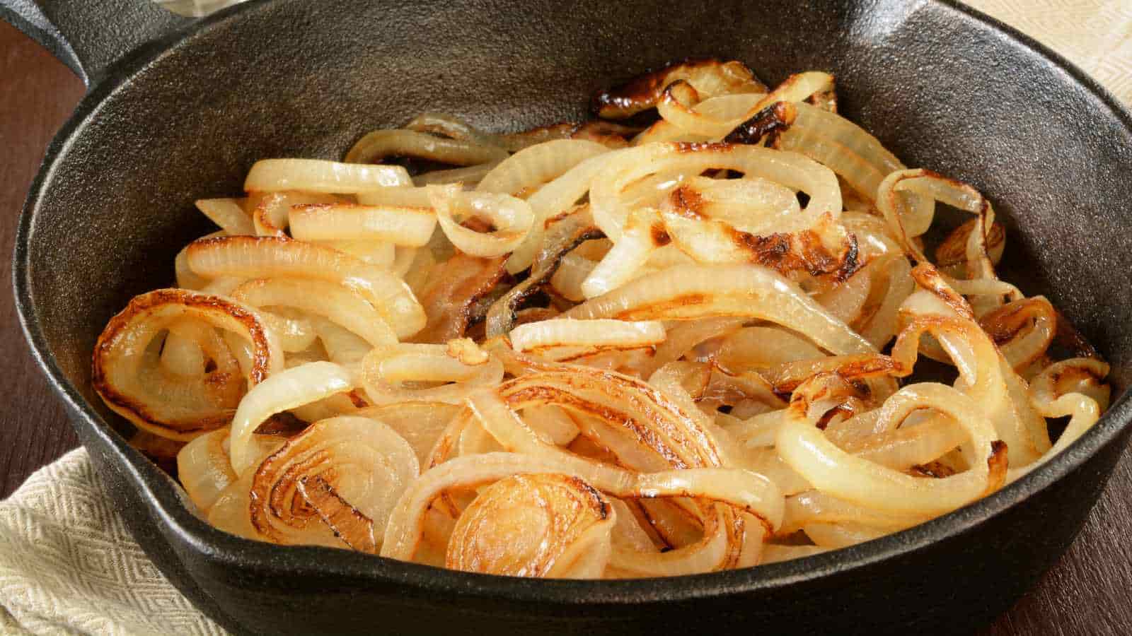 Sliced onions being caramelized in a cast iron skillet.