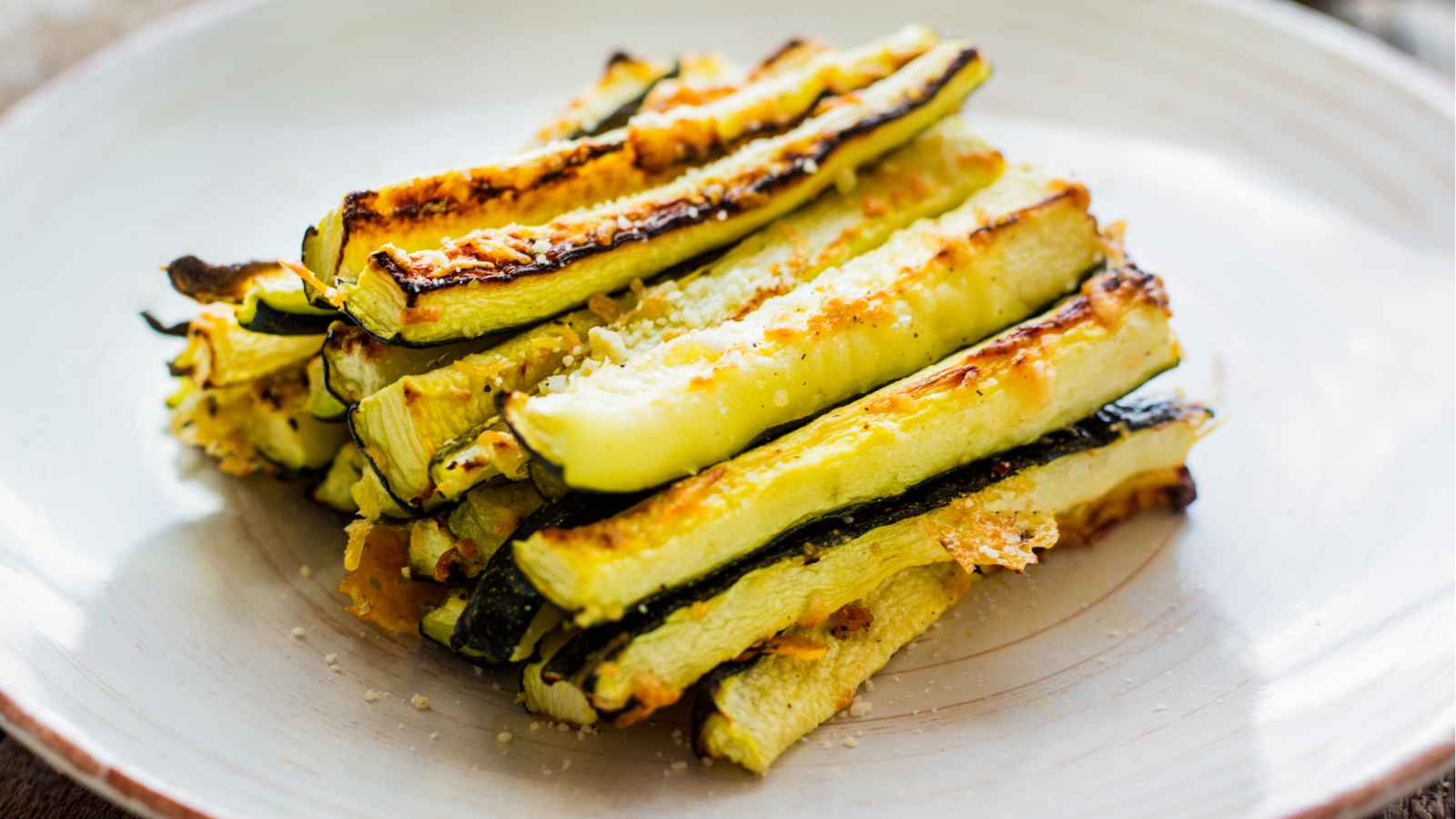 A stack of roasted zucchini strips on a white plate.