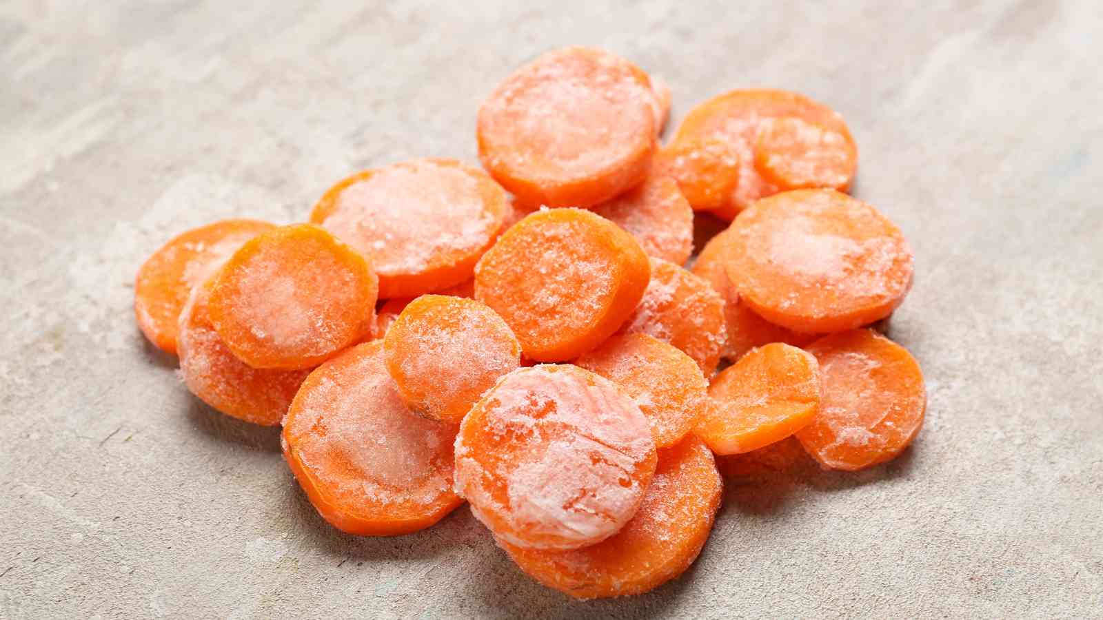 A pile of frozen carrot slices is arranged on a light-colored surface.