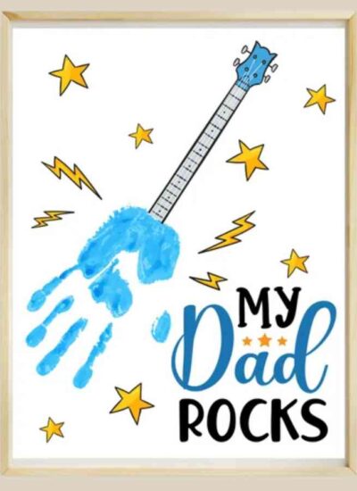 A framed artwork features a blue handprint shaped like a guitar with stars, lightning bolts, and the text "My Dad Rocks.