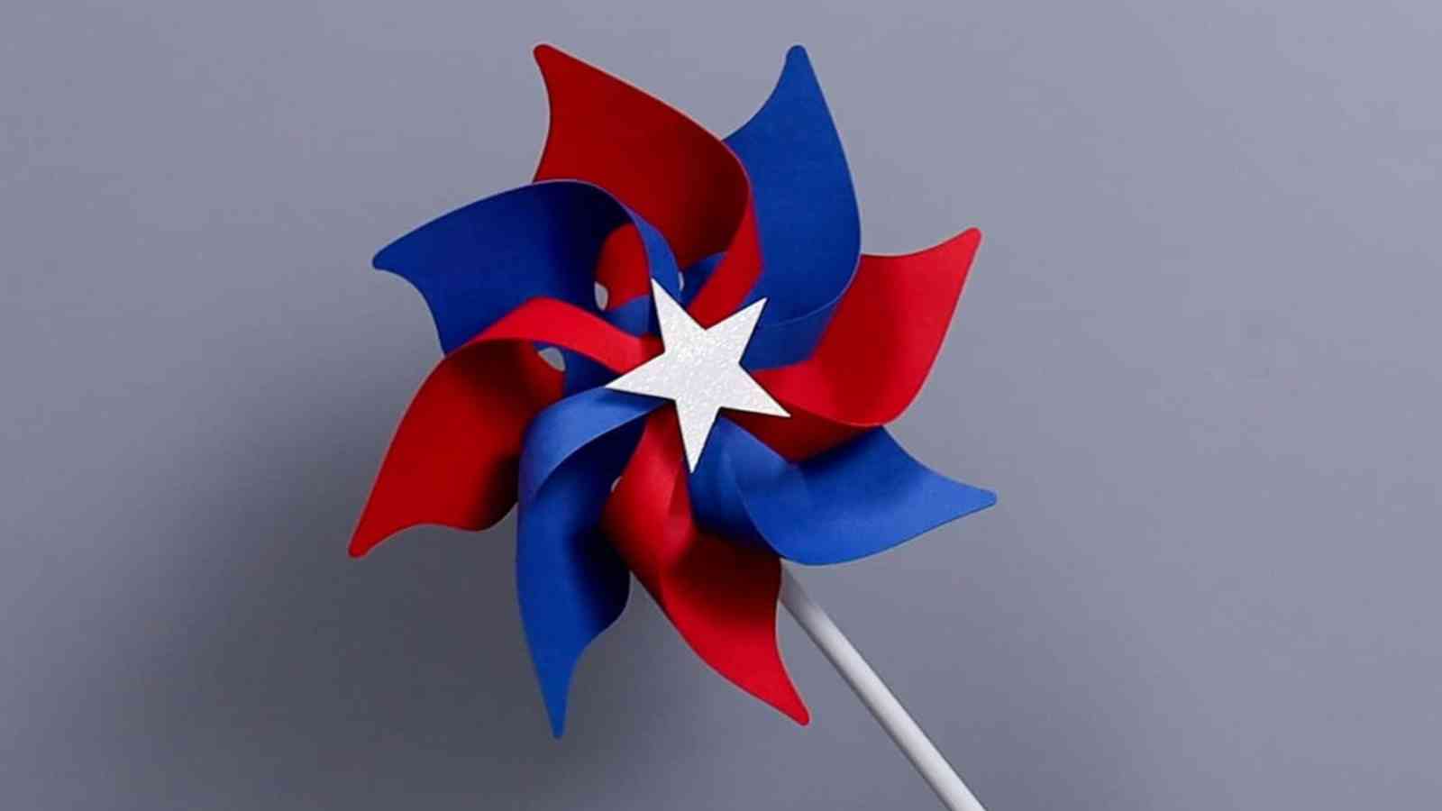 A red and blue pinwheel with a white star in the center, attached to a white stick, set against a gray background.