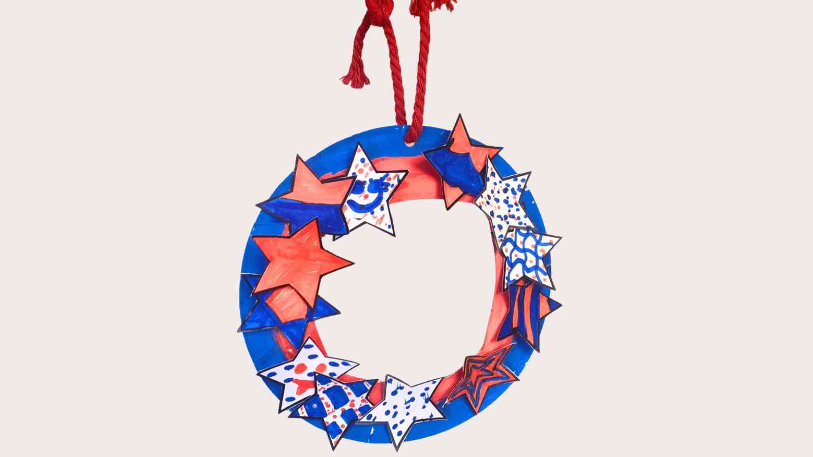 A circular wreath made of paper, decorated with red, white, and blue stars, hangs from a red string.