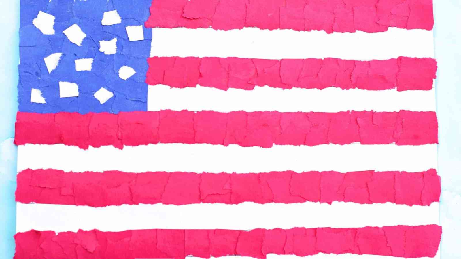 A handmade American flag collage made with torn pieces of red, white, and blue paper arranged on a flat surface.