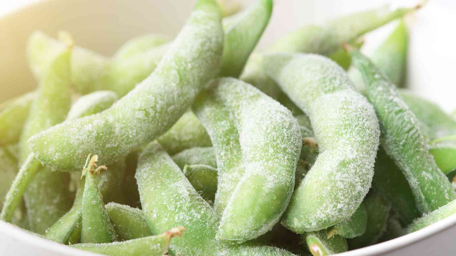Close-up of a bowl filled with frozen edamame pods, covered in a layer of frost.