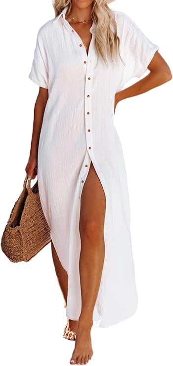 Woman wearing a white button-down maxi dress with short sleeves, holding a woven straw bag, and standing barefoot.