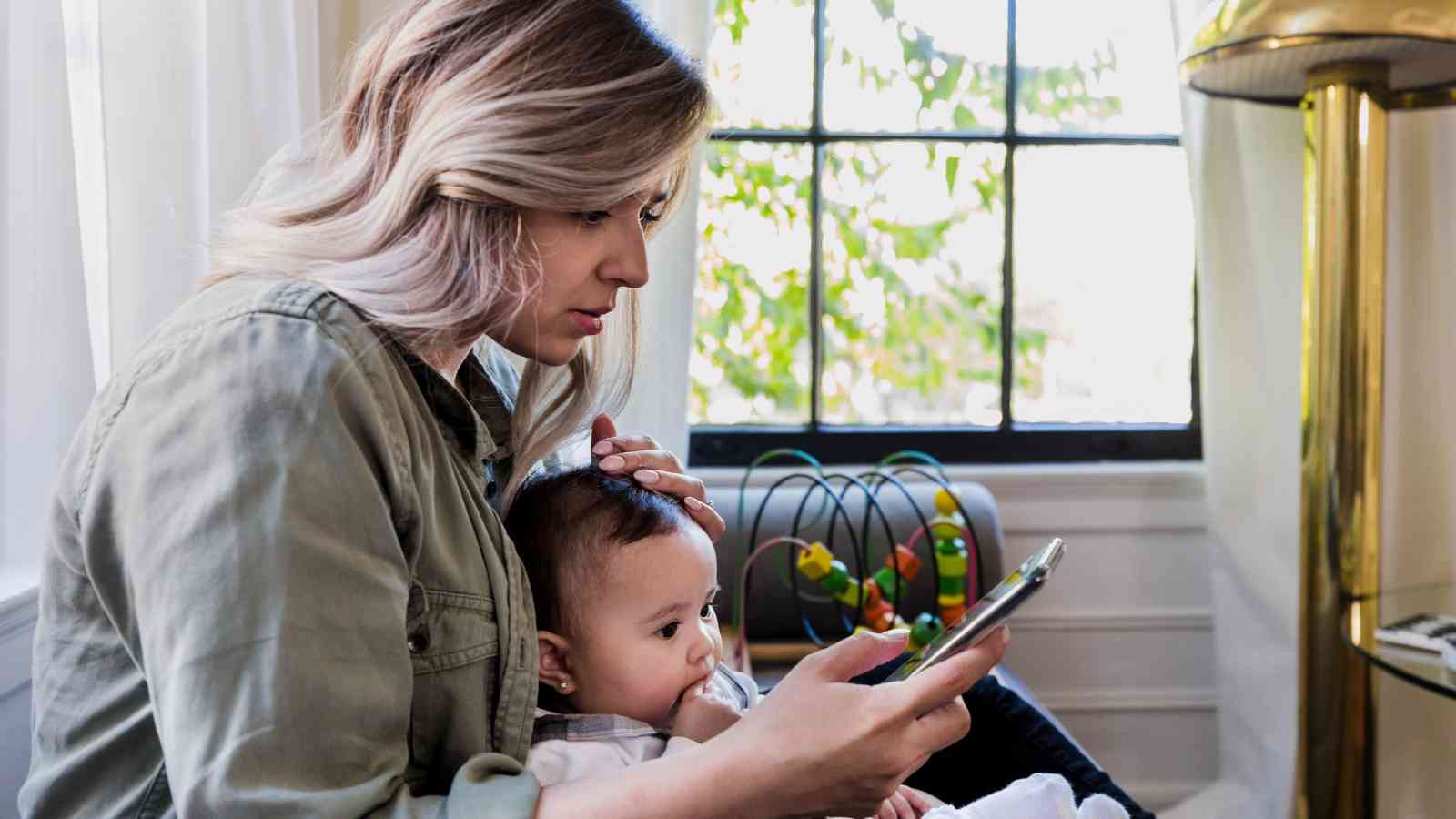 Mom with baby on her lap, scrolling on the phone.