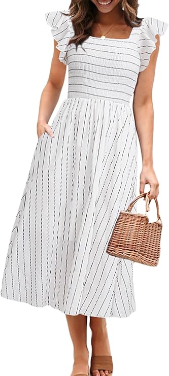 Woman wearing a white, ankle-length dress with black vertical stripes, ruffled sleeves, and a square neckline, holding a woven handbag and standing in sandals.