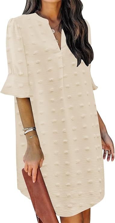 A woman wearing a cream-colored, textured short-sleeve dress with a V-neckline; she is holding a brown clutch.