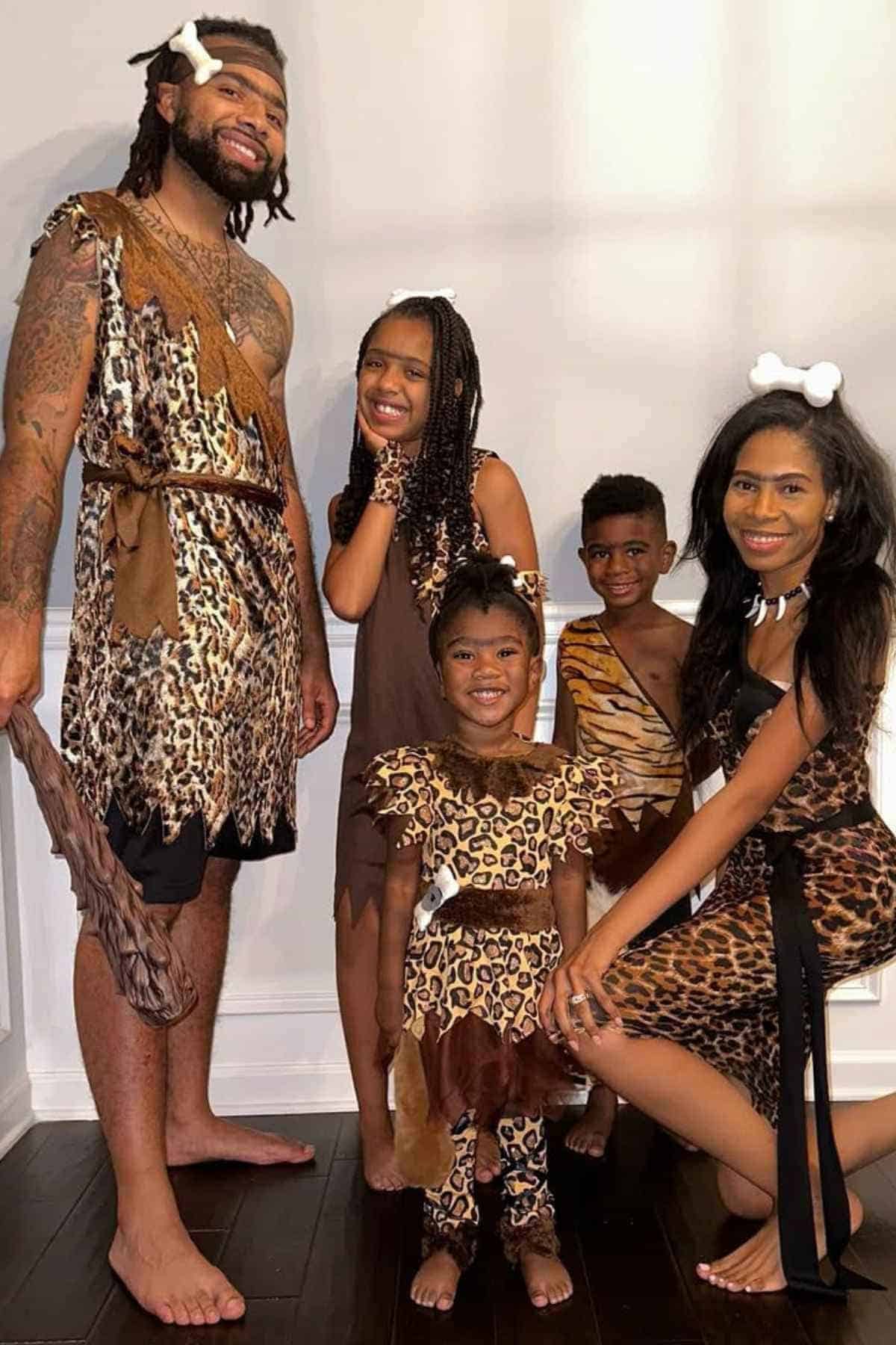 A family of five dressed in matching leopard print costumes, transforming them into a playful cave family.
