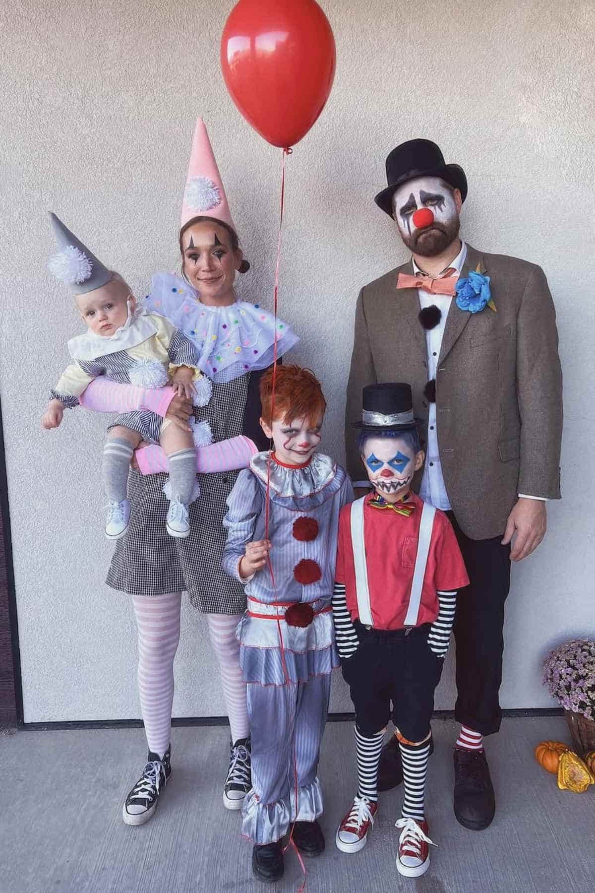 A family of five wearing clown costumes with face paints and hats.