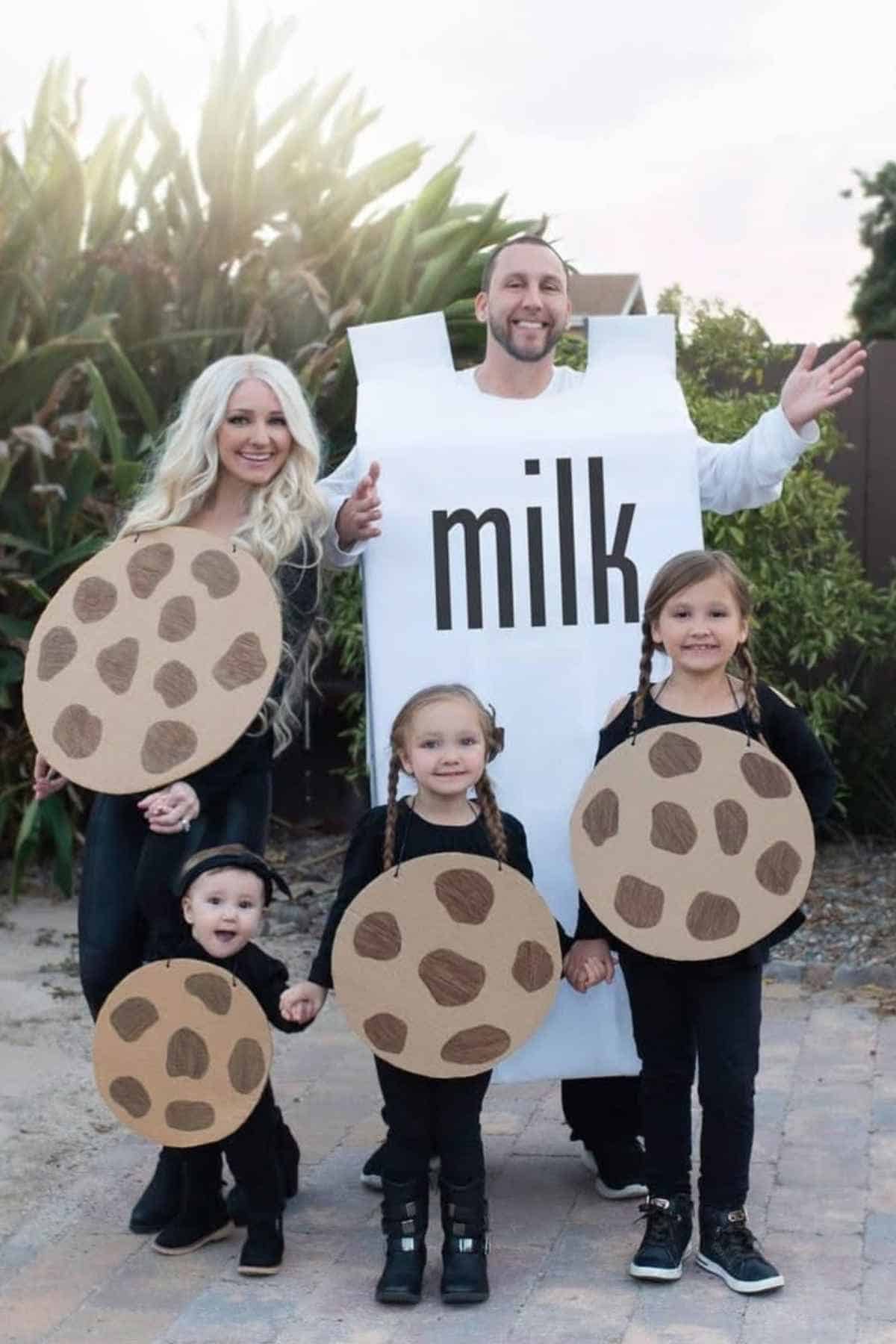 A family wearing halloween costumes, the Dad wears milk costume while mom and three kids wears a cookie costumes.