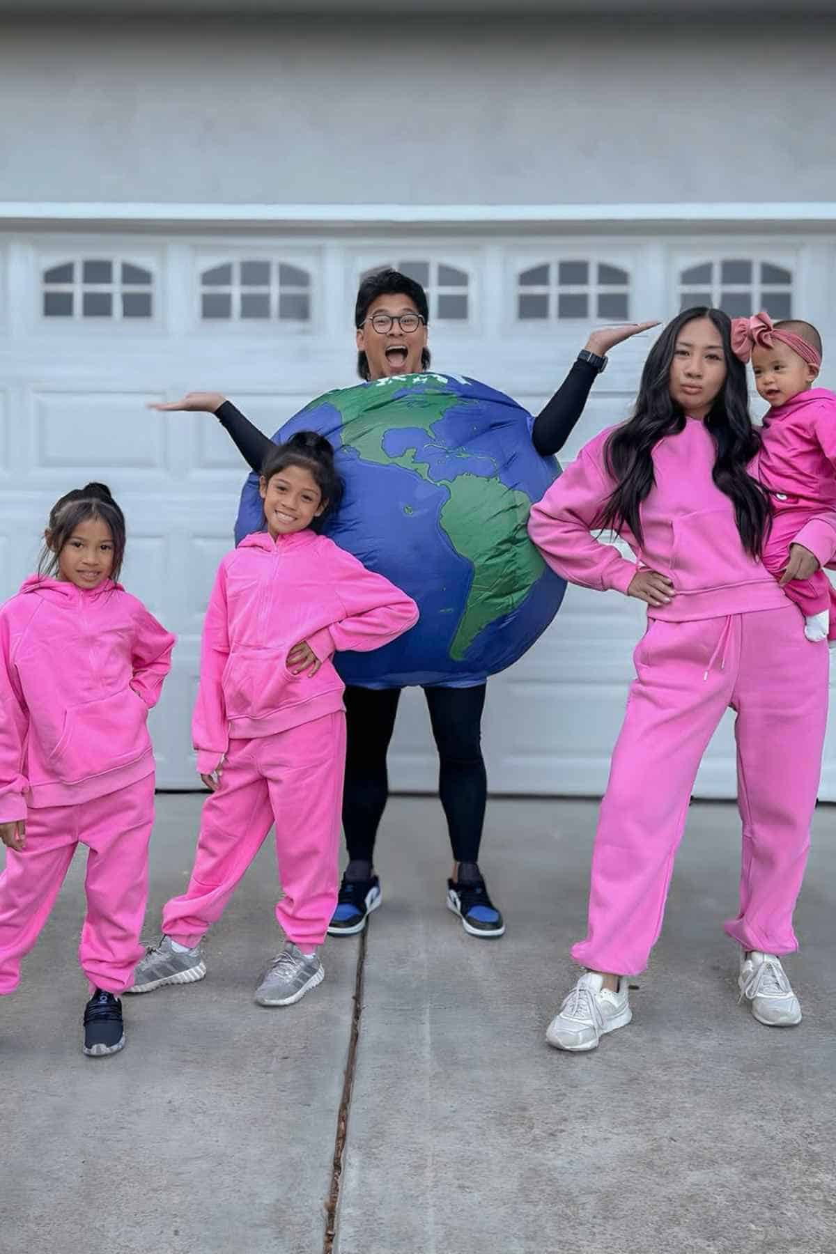 A family of five wearing wearing costumes, Mom and three kids wears pink and Dad wears a globe costume inspired the song entitled, "Run the World (Girls).