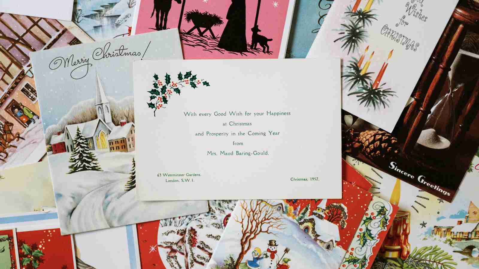 A pile of vintage Christmas cards with various winter scenes and holiday greetings are stacked together.