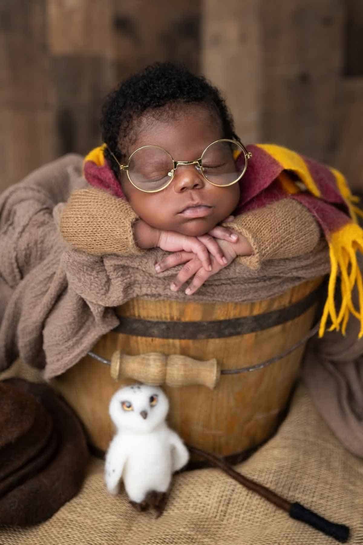 Baby wearing a glasses and dressed in a Harry Potter costume.
