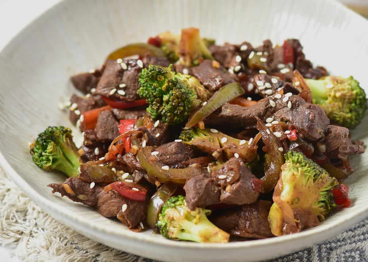 Venison stir fry served on a white textured plate.