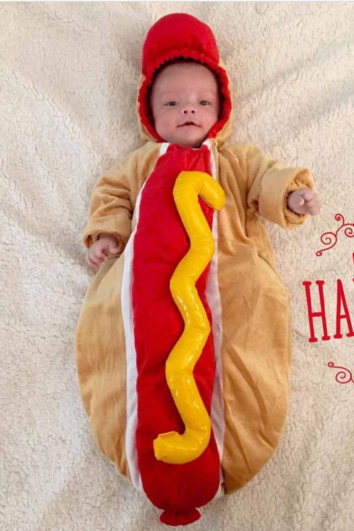 A baby wearing a hotdog sandwich costume.