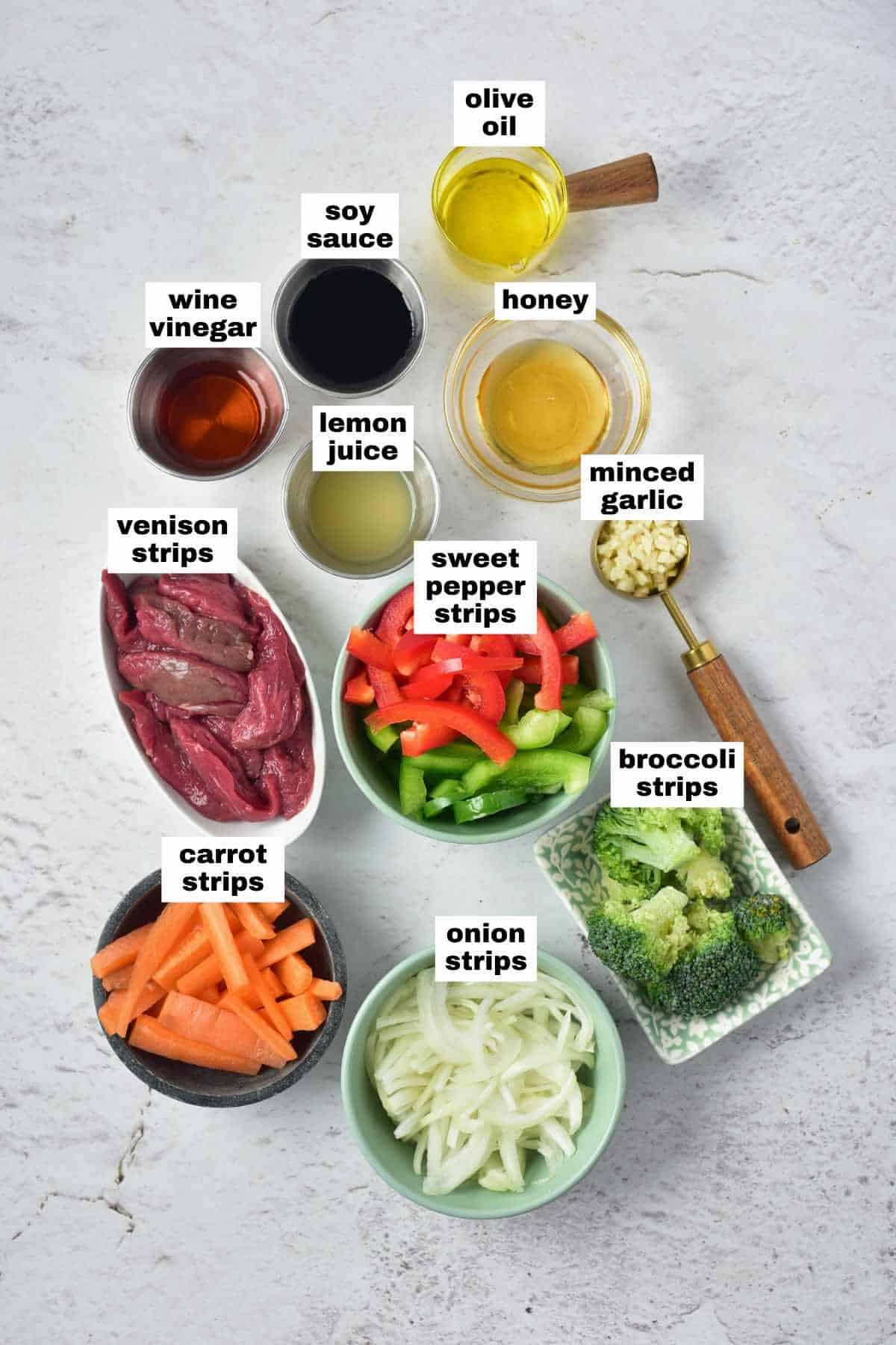 All the ingredients for the venison stir fry recipe arranged on a white surface.